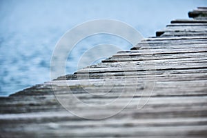 Closeup of the side of a wooden pier running diagonally across the frame with the lake visible in the background Variation 1