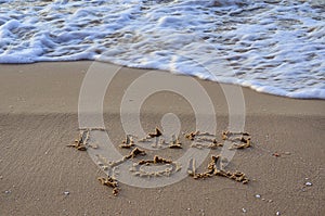 Closeup of a sign I miss you, written on sand. Wave on the beach