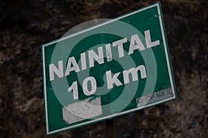 Closeup of sign with 'nainital 10km' text