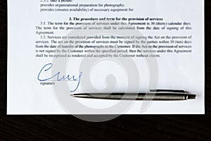 Closeup of signature and silver ballpoint pen with on document