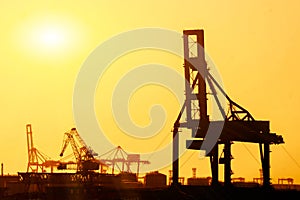 Closeup and silhouette of container and gantry crane at Osaka port are loading on evening