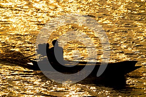 Closeup silhouette of fisherman boat in river on golden sunshine