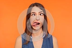 Closeup of silly dumb brunette woman demonstrating tongue and making stupid face with crossed eyes