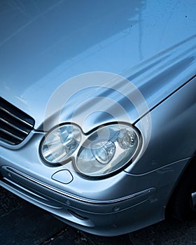 Closeup of a silver car with its headlights during the daytime