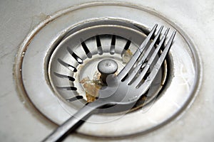 Closeup sink drain.Drain filter and a metal pipe sewer.Deep sink, dishwasher. Leftover food in the drain filter in the sink for wa