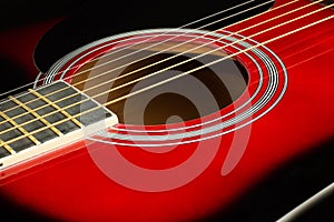 Closeup of a six stringed red acoustic guitar. Music entertainment background