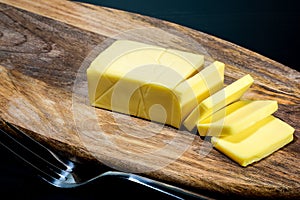 Closeup slice cheese on wooden board on black table background. Foods concept. Dark tone