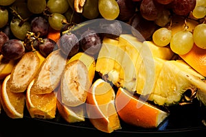 closeup sliced bananas, oranges, pineapples, and grapes