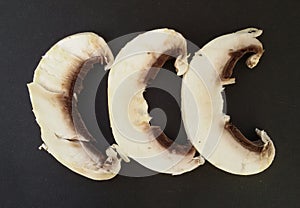 Closeup of sliced common mushrooms isolated over black. Fresh mushrooms ready for preparing.