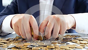 Closeup slow motion video of greedy businessman grabing coins lying on desk