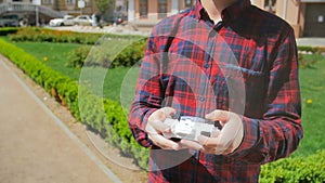 Closeup slow motion video of tiny toy drone taking off young mans hand in park. Teenager playing with small drone for