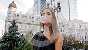 Closeup slow motion video of young woman blowing bigg bubbles from chewing gum