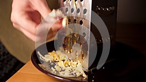 Closeup slow motion woman grates cheese on grater for pizza