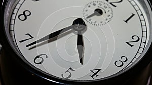 Closeup on slowly rotating clock face with fast moving clock hands - time running out