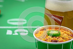 Closeup of a small bowl of chili and beer mug on table decorated