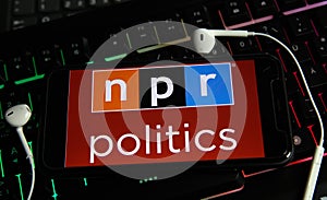 Closeup of smartphone screen with logo lettering of independant online radio broadcast service npr on computer keyboard