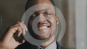 Closeup smiling black business man talking mobile smartphone in office. Close up of cheerful entrepreneur having phone