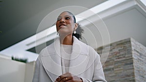 Closeup smiling black hair woman posing at modern house. Stylish girl wait taxi