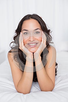 Closeup of a smiling brunette lying in bed