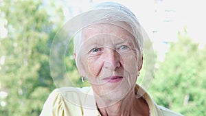 Closeup smiling caucasian senior woman posing at camera in summer day in garden. Senior lady looking straight. Older