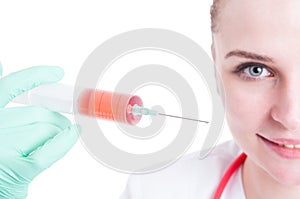 Closeup of smiling female doctor holding a syringe with liquid