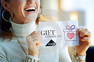 Closeup on smiling modern woman holding gift certificate