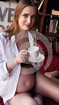 Closeup of smiling pregnant woman sitting with mug of tea