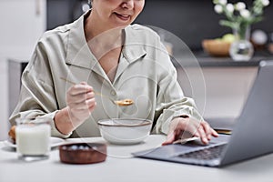 Closeup of smiling senior woman using laptop and working at home