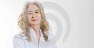 Closeup of smiling senior woman wrinkle face and gray hair. Old mature lady touching her wrinkled skin isolated on white