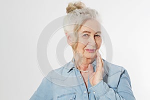 Closeup of smiling senior woman wrinkle face and gray hair. Old mature lady touching her wrinkled skin  on white