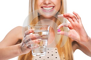 Closeup on smiling teenage girl giving cup of water and pill