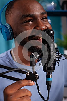 Closeup of smiling vlogger talking to audience using professional microphone wearing wireless headphones