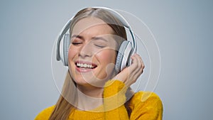 Closeup smiling woman listening music in headphones on grey background.