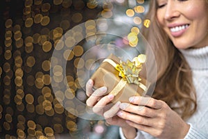 Closeup smiling young blonde woman holding luxury golden Christmas gift box celebrating holiday