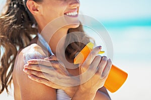 Closeup on smiling young woman applying sun block creme