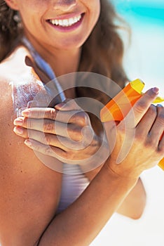 Closeup on smiling young woman applying sun screen creme