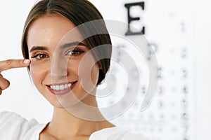 Closeup Of Smiling Young Woman In Front Of Visual Eye Test Board