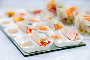 Closeup snacks at catering, banquet, buffet, finger food, shrimp, vegetable spring rolls in rice paper with peanut sauce in white