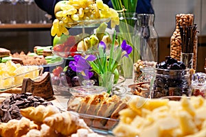 Closeup snacks, fresh and dried fruits, pieces parmesan cheese, honeycombs, dark chocolate, cinnamon sticks, nuts, biscotti.