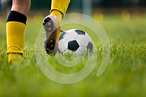 Closeup of soccer player running and kicking soccer ball on grass lawn