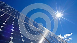 A closeup of a solar panel array glinting in the sunlight against a bright blue sky. The panels are carefully angled to