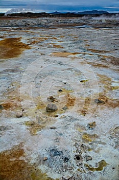 Closeup of solfatare mudpot s in the geothermal area Hverir, Iceland. The area around the boiling mud is multicolored and cracked