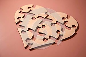 closeup of some separated pieces of a puzzle which together form a heart on a white rustic wooden surface