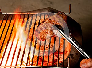 Closeup of someone turning a tasty steak cooking on a fire