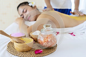 Closeup on spa therapy ingredients and relaxed young woman in background