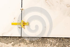 Closeup on spacer between floor tiles for consistent grout gap