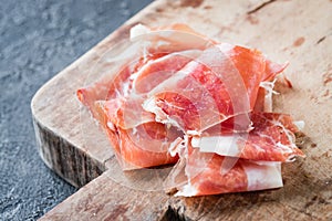 Closeup of Spanish ham jamon serrano or Italian prosciutto crudo on old wooden board