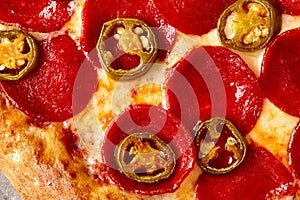 Closeup of spicy pizza with pepperoni, tomato sauce, mozzarella and jalapeno