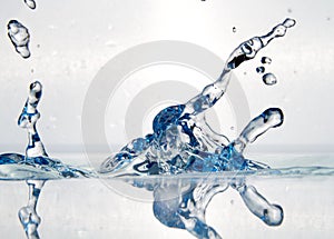 Closeup of splashing water under the lights on a white background