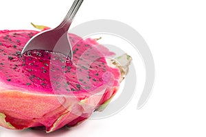 Closeup of a spoon in a red dragon fruit cut in half isolated on a white background